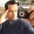 Pixelated image of a person with short dark hair wearing a dark blue shirt, holding a camera with a large lens toward the viewer.