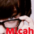 A person with dark hair and glasses adjusts their glasses with a hand, with red and yellow text reading "Mlcah" and "Micah" below.