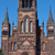 Pixelated image of a stone cathedral with tall spires and arched windows against a clear blue sky.