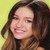 A static pixelated image of a person with long brown hair smiling, set against a light yellow background.