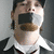A person with a black gag over their mouth appears on the left side of a split-screen image, while bold white text reads "SHUT UP!" on a red background to the right.