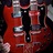 Pixelated static image of a red electric guitar with metallic components and dark background elements.