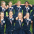 Group of people in dark blue uniforms with white collars posing outdoors on grass, two versions show text overlays.