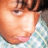 Pixelated close-up of a person's face with light brown hair, pink lips, and a light blue patterned background.