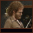 Animated contact sheet showing a man with curly hair in a beige suit speaking, with text changing across frames from 'More' to 'Cowbell!'