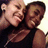 Two people in black sleeveless tops pose closely together, smiling with eyes closed in a pixelated image.