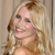 Pixelated close-up of a smiling person with long blonde hair against a light brown background.