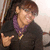 A person in a black jacket and purple scarf makes a hand gesture, with background variations across frames.