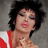 Pixelated image of a person with dark curly hair wearing a red and white top, next to bold red text reading DEAD OR ALIVE on a gray background.