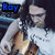A person with long dark hair plays a light brown string instrument while wearing a white shirt, with blue text reading 'Roy' in the top-left corner.