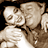 Static pixelated image of two figures in close physical contact with visible facial features and partial body outlines against a dark background.