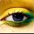 A pixelated close-up of a human eye with blue iris, green and yellow eyelid shading, set against warm golden-brown background.