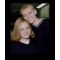 A static image of two people in a dark setting with a light source above them, displayed as a small square frame.