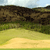 Pixelated landscape with layered terrain, green grassy foreground, brown rocky middle ground, and light blue sky background.