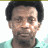 Pixelated image of a person with short dark hair wearing a light green shirt against a white background, next to blue text on black and gray backgrounds.
