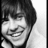 Black-and-white photo of a person with short dark hair smiling, displayed in a