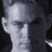 Pixelated grayscale portrait of a person with short hair, visible ear, and partial neck against dark background.