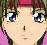 Pixelated close-up of a character's face with large blue eyes, brown hair, and a pink headband against a green background.