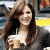 A pixelated static image shows a person with long brown hair holding a white cup with a straw, wearing a dark top against a blurred background.