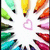 A static pixelated image shows a circular arrangement of colorful pencil-like objects surrounding a central pink heart shape on a white background.