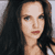 Static pixelated image of a person with long dark hair and light skin, cropped to show upper body against gray background.
