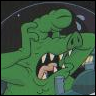 Green cartoon alien with large eyes and sharp teeth, mouth open in a roar, holding a small figure in its hand against a dark background.