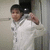 A pixelated static image shows a person in a white shirt with dark hair, holding an object near their head against a light background.