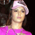 Pixelated image of a person wearing a light pink cap and bright pink top against dark background.