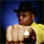 Pixelated figure wearing black cowboy hat, yellow cape, and dark vest over light shirt, standing against blue and black background.