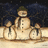 Animated snowman scene with three figures on a snowy base under dark sky, text 'Let It Snow' in cyan above and below.