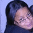Pixelated close-up of a person with dark hair against light blue background, showing partial face and shoulder.