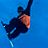 Pixelated figure in dark clothing performing a snowboarding trick against solid blue background.