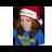 A person wearing a red and white Santa hat with a white pom-pom, brown hair, blue shirt, and yellow patterned chest area.