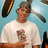 Pixelated image of a person wearing a white t-shirt with a small graphic, holding an object against a light blue background.