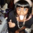 Pixelated static image of a character with dark hair wearing a dark jacket, giving a thumbs-up gesture with one hand and holding a glowing white object in the other.