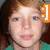 Pixelated close-up of a person with light brown hair wearing a green top and dark necklace, orange icon overlay on right.