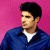 Pixelated image of a person in blue jacket over white shirt against pink background, with green text reading Original Icons .com on dark green