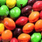 colorful candy-coated chocolate pieces with visible text reading 'SKITTLE' and '!!!!' on a gray background