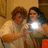 Two figures in a dimly lit indoor setting, one holding a bright light source that obscures part of the scene.
