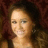 Pixelated close-up of a person with light skin tone, dark hair, and a neutral expression against a dark brown background.