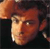 Pixelated close-up of a person's face with warm brown and orange tones, dark background, and visible pixelation artifacts.