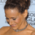 Pixelated close-up of a person with short dark hair, light skin, and a thin dark necklace against a light blue background.