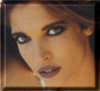 A woman's face with dark eye makeup and purple lips appears in a static frame, followed by showing her head turning left to right against warm-toned backgrounds