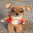 Pixelated static icon of a small dog with angel wings and halo, wearing red heart-shaped accessories on its chest against a checkered background.