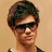 Pixelated image of a person with dark hair and sunglasses on a beige background, next to heart symbols and text elements.