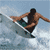 A 4-frame contact sheet animation of a shirtless surfer performing tricks on a white surfboard against ocean waves, displayed in a 2x2 grid layout with gray transparency background.