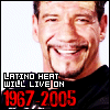 Pixelated close-up of a smiling person with short dark hair and goatee, wearing black shirt against white background.