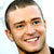 Static pixelated close-up of a smiling man's face with short dark hair and light skin, cropped to show head and upper neck against a white background.