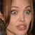 Pixelated close-up of a person with light brown hair, fair skin, and visible eyes and mouth against a dark background.