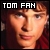 Pixelated close-up of a person's face with light brown hair, wearing dark clothing and red accents, under bold white text reading TOM FAN on black background.